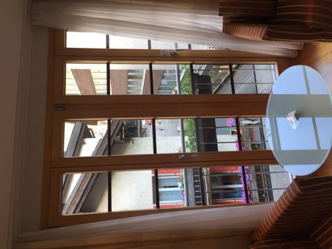 View through glass doors over a narrow alpine street lined with balconies and flowers