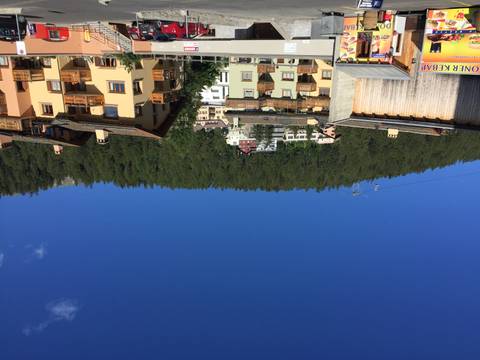 Clear blue sky above alpine village houses with forested hillside and cable car wires
