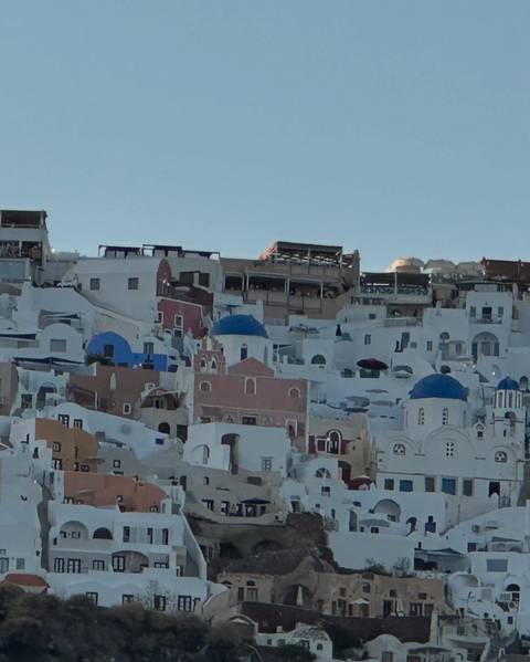 Whitewashed houses and blue-domed churches clustered on a Santorini cliffside.