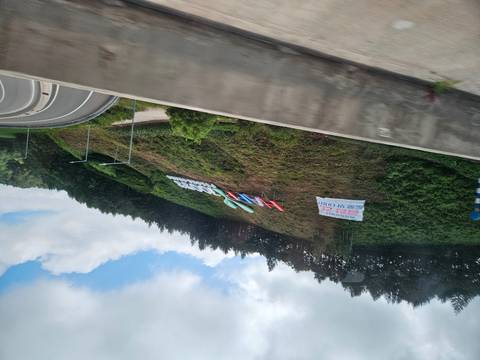 Roadside hillside with a large colorful "Happy" sign photographed through a moving vehicle window.
