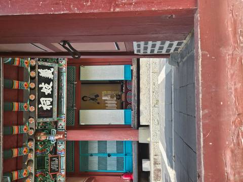Entrance of a traditional Korean wooden building with colorful painted beams and open doors.