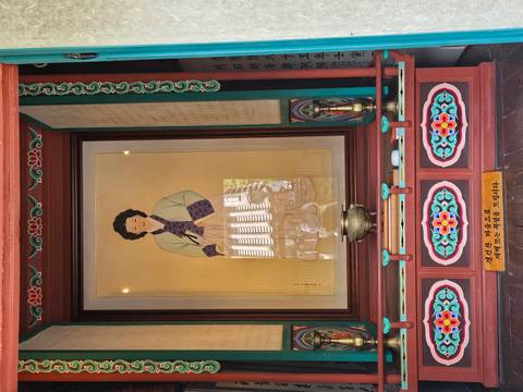 Framed portrait of a woman in traditional dress displayed inside an ornate wooden shrine.