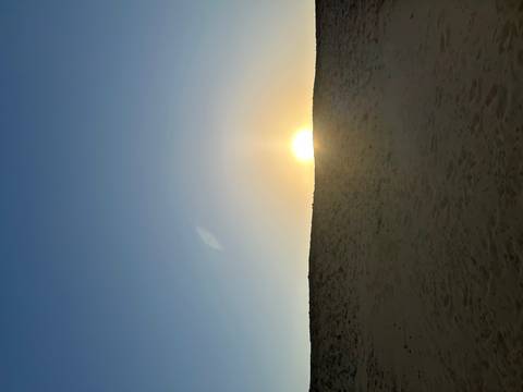 Rising sun just above a low sandy ridge in the desert creating a soft glow