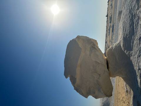 Large white rock pedestal formation in bright desert sunlight with deep blue sky