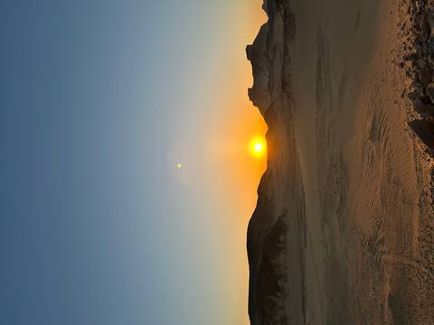 Golden desert sunset over rolling sandy hills and distant mesas