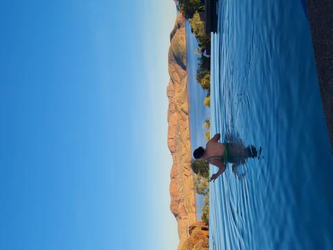 Woman relaxing in infinity pool overlooking Lake Argyle and red hills