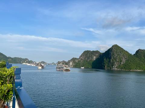 Cruise boats navigate the calm blue waters surrounded by towering limestone karsts in Ha Long Bay.