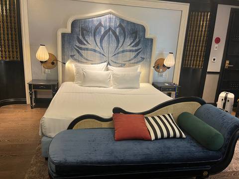A stylish hotel room featuring a lotus-themed headboard, crisp white bedding and colourful accent cushions.