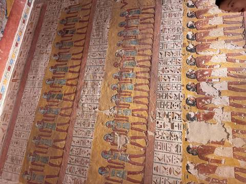 Tomb wall covered with rows of painted human figures and hieroglyphic columns.