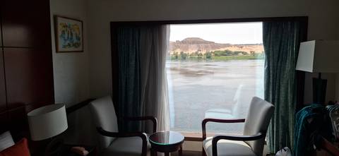 Cruise cabin sitting area with two chairs facing a large window overlooking the Nile River.