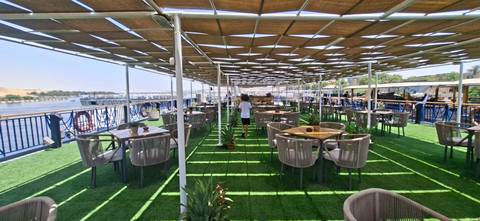 Open-air dining deck on a Nile cruise ship with green turf flooring and river views.