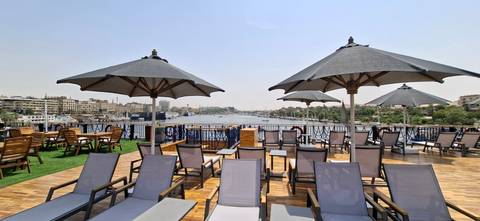 Cruise ship sun deck with loungers facing a riverside cityscape.
