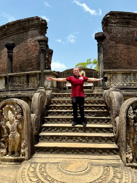 Traveler posing on ornate stone staircase of an ancient circular temple