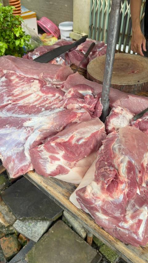 Close shot of raw cuts of pink meat displayed on a market table.