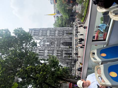 St. Joseph Cathedral in Hanoi viewed from an open-top bus with crowds outside.