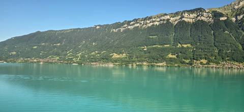 Tranquil turquoise lake bordered by forested mountains near Interlaken, Switzerland.