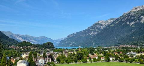 Panoramic view over Interlaken toward turquoise Lake Thun set against surrounding alpine mountains.