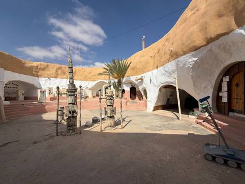Sunlit troglodyte courtyard in Matmata displaying Star Wars movie props against blue sky.