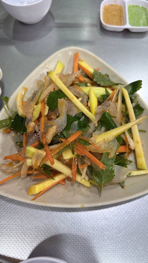 Plate of spicy Vietnamese jellyfish salad with mango, herbs, nuts and lemongrass.