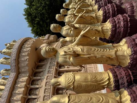 Row of golden Buddha statues encircling temple structure with detailed plinths.