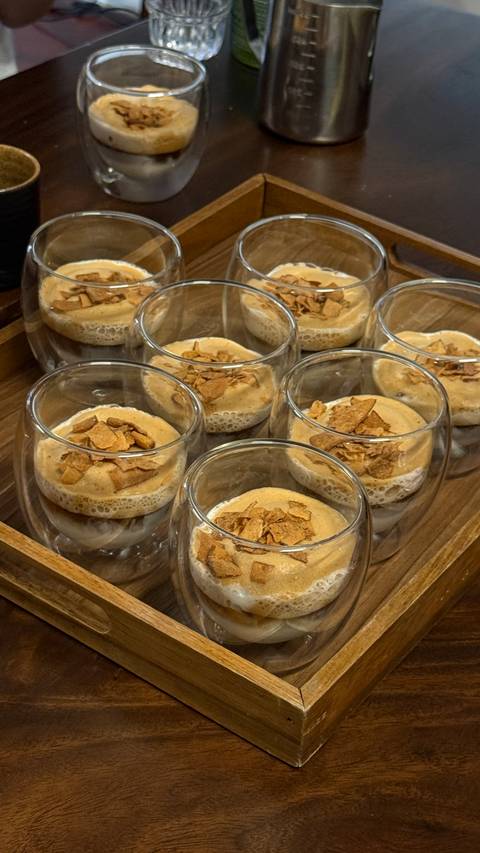 Row of glass cups filled with creamy Vietnamese egg coffee topped with crunchy flakes.