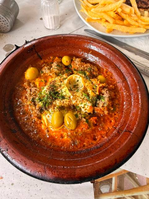A bubbling Moroccan tagine filled with meat, egg, olives and rich red sauce.