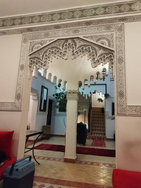 Ornate white stucco arches and detailed Moorish patterns inside a Moroccan riad.