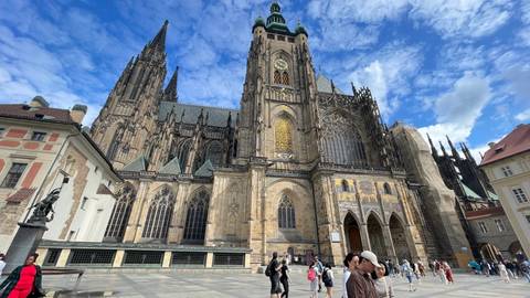 Wide view of St. Vitus Cathedral exterior with tourists walking across the spacious square.