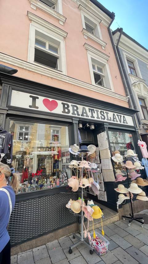 Storefront sign reading 'I ♥ Bratislava' above souvenir hats and trinkets.