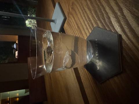Close-up of a glass of sparkling water with ice on a wooden table in dim lighting.
