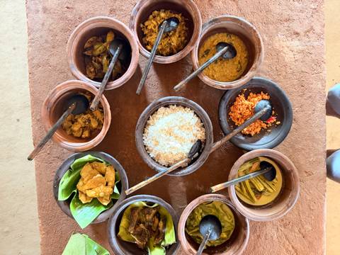 Overhead view of assorted Sri Lankan curries, rice and condiments served in rustic clay pots