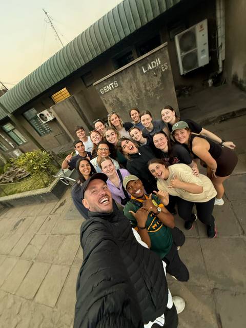 Large group of smiling travellers gather for a cheerful street selfie.