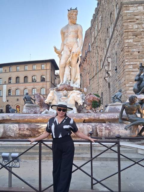 Woman in sunhat standing by the Fountain of Neptune surrounded by Renaissance statues