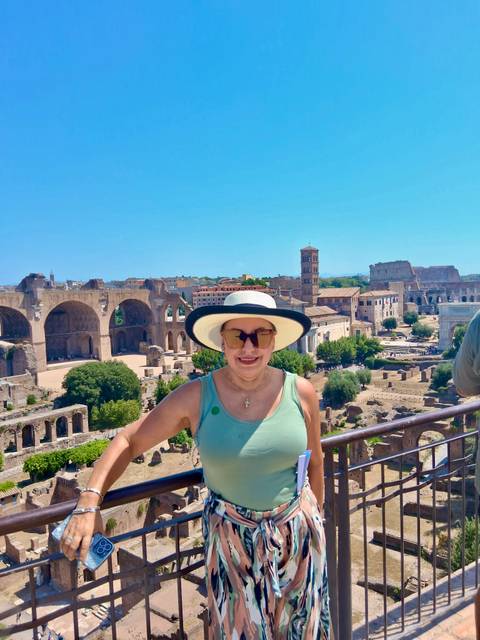 Traveler in hat overlooking the Roman Forum ruins with city skyline behind