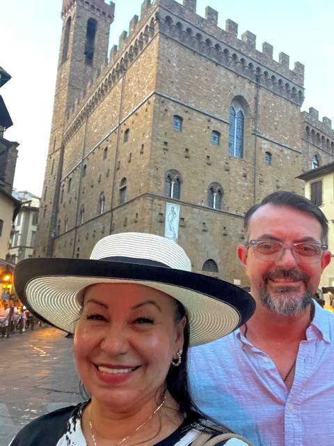 Evening selfie of a couple with historic stone building illuminated in the background