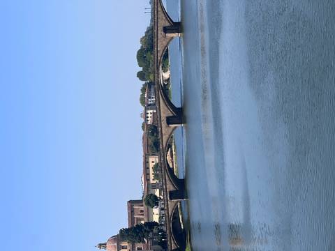 Stone arch bridge spanning a calm river under clear blue sky
