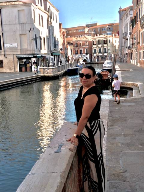 Woman leaning on stone ledge beside quiet canal lined with historic buildings