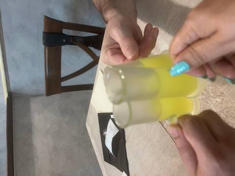 Hands toasting small glasses of yellow limoncello inside a casual restaurant