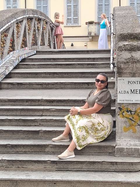 Woman sitting on worn stone steps decorated with mosaic literary quotes