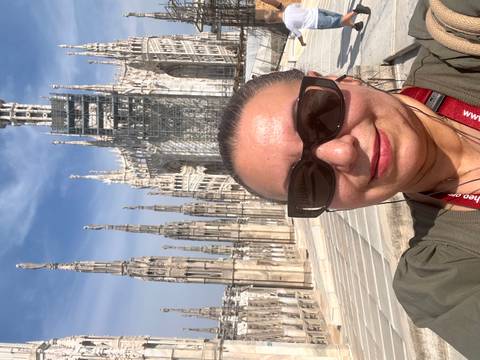 Woman taking selfie on rooftop terraces of Milan Duomo with soaring spires behind