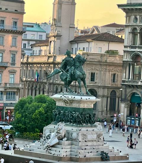 Equestrian statue of King Victor Emmanuel II rising above green trees in city square