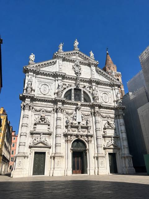 Elaborate white stone baroque church facade with blue sky backdrop