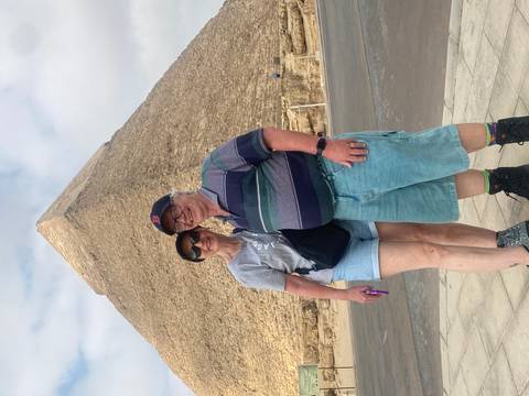 Couple standing in front of the massive pyramid blocks for a vacation photo.