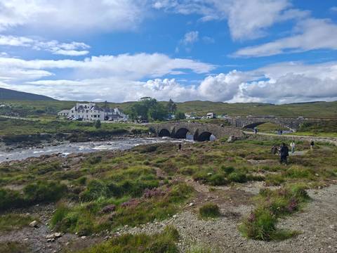 Historic stone bridge over a rocky river with travellers exploring the scenic moorland