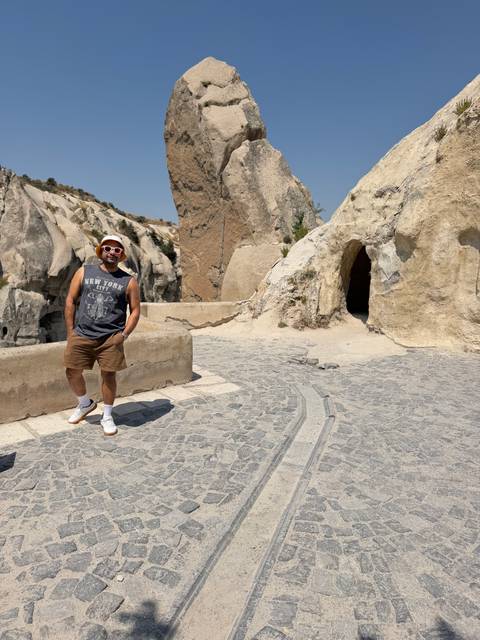 Traveler posing on a cobblestone path among Cappadocia's soft tufa rock cliffs