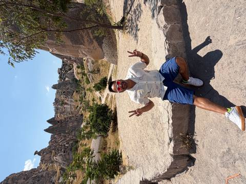 Smiling tourist flashing peace signs in a valley of pointed rock spires in Cappadocia