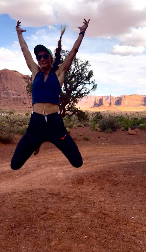 Partial view of a jumping person against the red mesas of Monument Valley at dusk