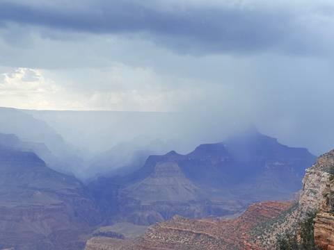 Grand Canyon layers fading into mist with a rainstorm sweeping across the cliffs