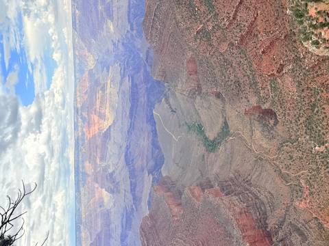 Panoramic view into the vast Grand Canyon with a winding trail and exposed layers