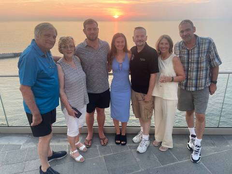 Family group poses at sunset on a terrace overlooking the Amalfi Coast and sea.